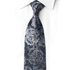 Midnight navy silk necktie knotted against a white shirt, with silver-gray floral scrollwork and crystal rhinestone accents.