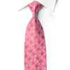 A pink necktie with a white floral pattern, styled in a knot on a white collared dress shirt against a white background.